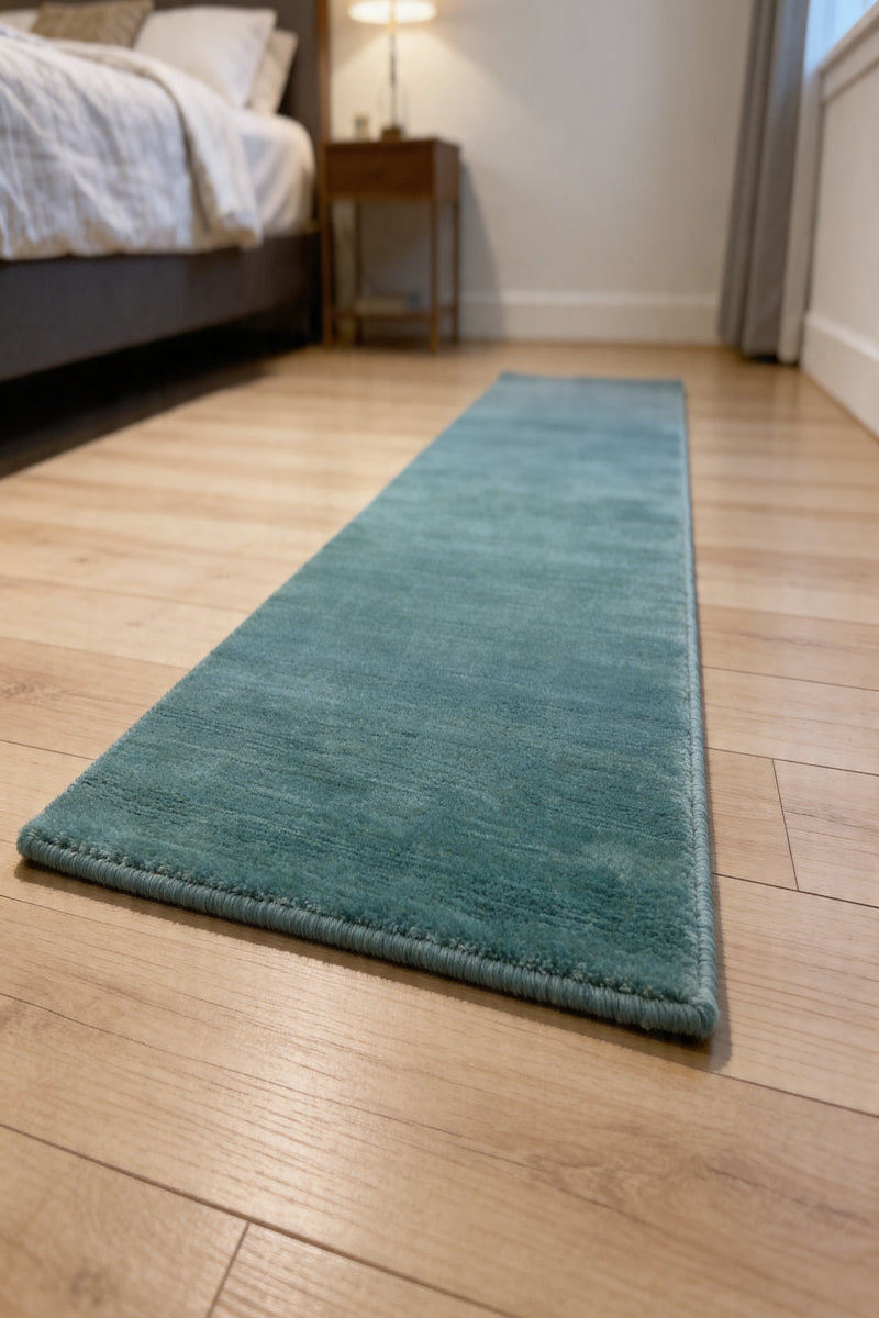 Teal runner rug on a wooden floor in a bedroom setting